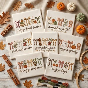 May include: Seven rectangular white fabric canvases featuring embroidered autumn-themed designs, including bows, pumpkins, ghosts, and text such as cozy book season, pumpkin patch, orchard season, pumpkin spice, cozy and spooky, cozy season, and cozy days.