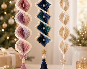 May include: Three hanging spiral ornaments crafted from crochet yarn. The left is a pink gradient, the center is a blue gradient with a gold star, and the right is cream-colored. Each features a wooden bead, a tassel, and a hanging loop at the top.