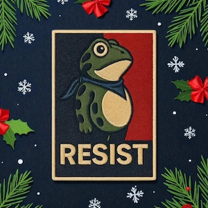 May include: Embroidered patch featuring a green frog wearing a blue scarf, set against a red and black background. The word "RESIST" is displayed in tan letters below the frog. The patch is surrounded by Christmas decorations.