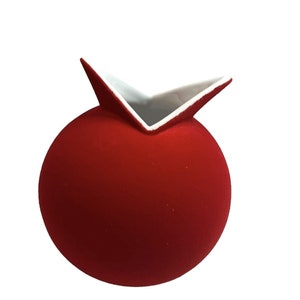 May include: A red, spherical vase with a unique, angular opening. The exterior is a matte red, while the interior of the opening is white. The vase has a modern, minimalist design, suitable for home decor.