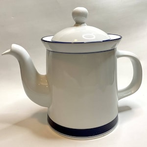 May include: White ceramic coffee pot with a lid and handle. The pot has a blue stripe around the base and a blue trim around the top. The spout is long and curved. The lid has a small knob on top.