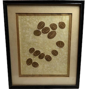 Puede incluir: Obra de arte enmarcada con ilustraciones de escarabajos de la patata marrones sobre un fondo beige moteado. La obra está firmada y fechada en el '60, con el título 'Potato Beetles'. El marco es negro con un borde interior dorado.