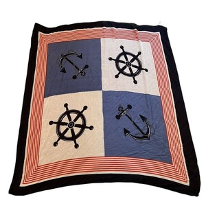 May include: Square nautical scarf with a navy blue, white, and red color scheme. The scarf features four squares, alternating between white and blue, each with a black anchor or ship's wheel design. The border is red and white striped, with a black outer edge.