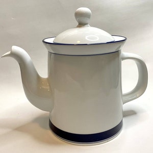 May include: White ceramic coffee pot with a lid and handle. The pot has a blue stripe around the base and a blue trim around the top. The spout is long and curved. The lid has a small knob on top.