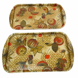 Può includere: Due vassoi rettangolari con angoli arrotondati. I vassoi presentano uno sfondo color crema con un motivo ripetuto di frutta, foglie e forme geometriche nelle tonalità dell'arancione, del marrone e dell'oro.