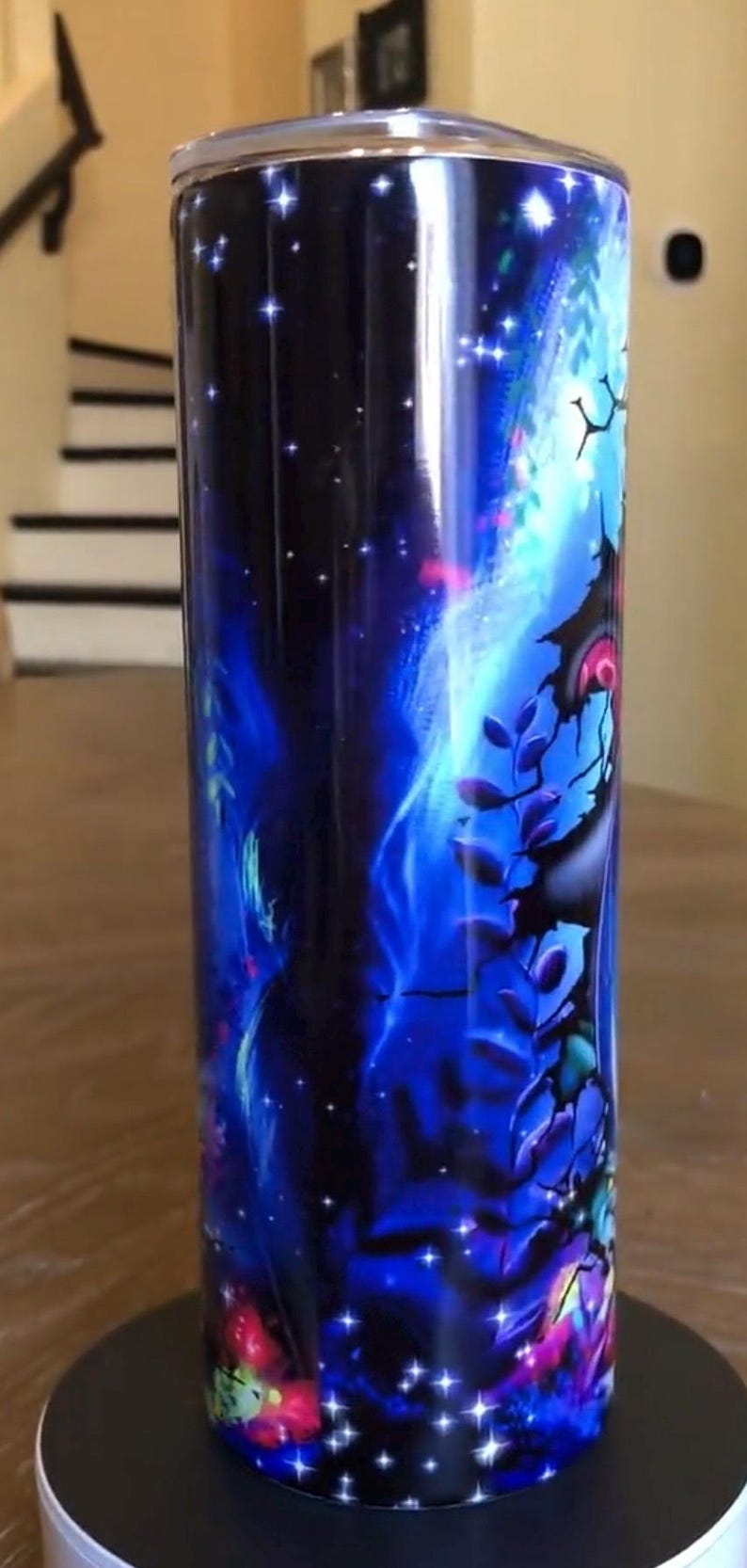Puede incluir: Un vaso de acero inoxidable con un dise&ntilde;o de galaxia azul y negro. El vaso presenta un cielo nocturno estrellado con una nebulosa giratoria y una silueta de &aacute;rbol.