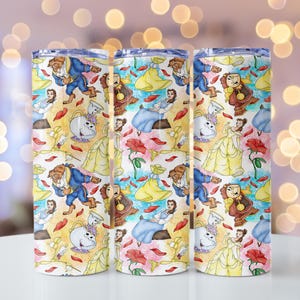 May include: Three stainless steel tumblers with a colorful pattern featuring characters and elements from a fairy tale. The design includes illustrations of a beast, a princess in a yellow gown, and other characters, along with red rose petals.