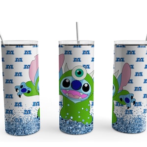 May include: A white tumbler with a blue glitter bottom. The tumbler features a cartoon character with blue fur and a green monster costume. The character has a single large eye and a small mouth. The background is a white pattern of blue eyes.