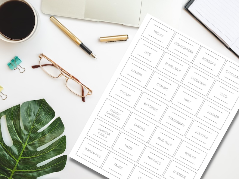 Op de afbeelding: Een vel witte etiketten met zwarte tekst voor het organiseren van kantoorbenodigdheden. Labels zijn onder meer "Tissues", "Tape", "Erasers", "Staples", "Kabels/Opladers", "Visitekaartjes", "Garanties" en meer. Ook een pen, een bril en een kopje koffie zijn zichtbaar.