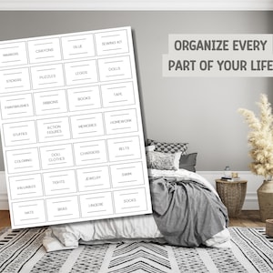 Op de afbeelding: Een witte labelorganizer met diverse opslagcategorie&euml;n, waaronder "Markers", "Crayons" en "Legos". De tekst "Organize Every Part of Your Life" wordt weergegeven boven een bed met een grijze deken en een patroonkleed.