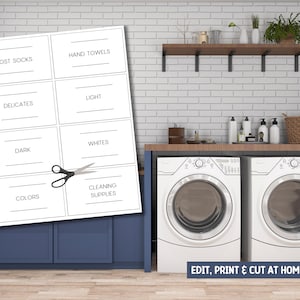 Op de afbeelding: Een wasruimte met een witte bakstenen muur en blauwe kasten. Een vel bedrukbare waslabels met tekst als "Lost Socks" en "Hand Towels" staat op de voorgrond. Een schaar ligt naast de labels. Twee witte wasmachines staan in de kamer.