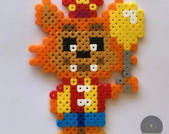 May include: A pixel art character made with colorful beads. The character is a brown bear wearing a red and yellow life vest, a red hat, and holding a yellow balloon.