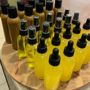 May include: A collection of amber and yellow glass bottles with dropper tops and spray tops. The bottles are arranged in a circular pattern on a wooden surface.