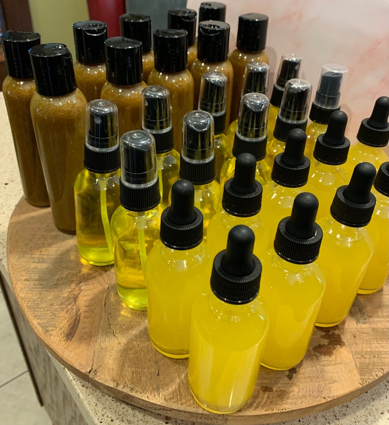 May include: A collection of amber and yellow glass bottles with dropper tops and spray tops. The bottles are arranged in a circular pattern on a wooden surface.