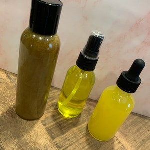 May include: Three glass bottles with yellow liquid and black caps. The bottles are on a wooden surface.
