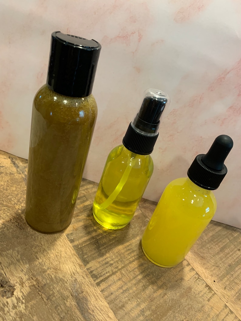 May include: Three glass bottles with yellow liquid and black caps. The bottles are on a wooden surface.
