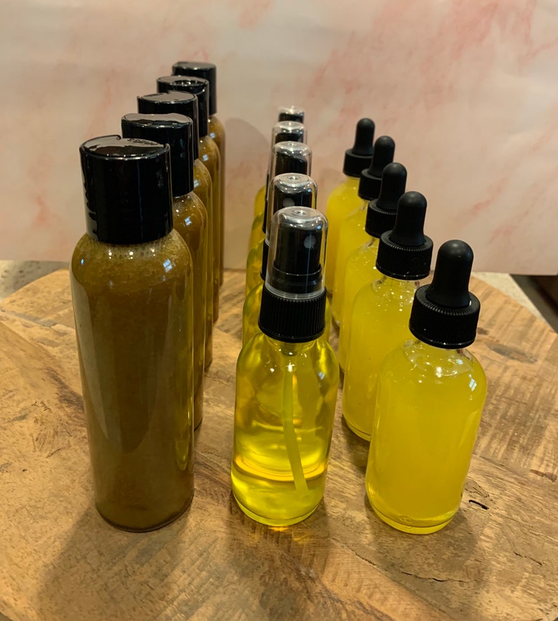 May include: A collection of amber and yellow glass bottles with black caps and droppers. The bottles are arranged in a row on a wooden surface.
