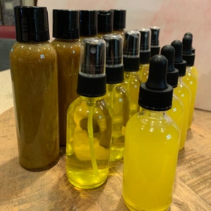 May include: A collection of amber and yellow glass bottles with black lids. Some bottles have a spray nozzle, while others have a dropper.