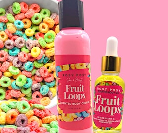 May include: A set of two pink and yellow body care products with a fruity scent. The products are labeled "Fruit Loops" and are a scented body cream and a scented body oil. The products are in front of a bowl of colorful cereal.