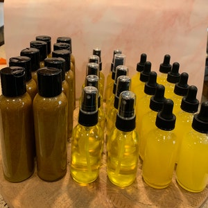 May include: A collection of amber and yellow glass bottles with black caps and spray tops. The bottles are arranged in rows on a wooden surface.