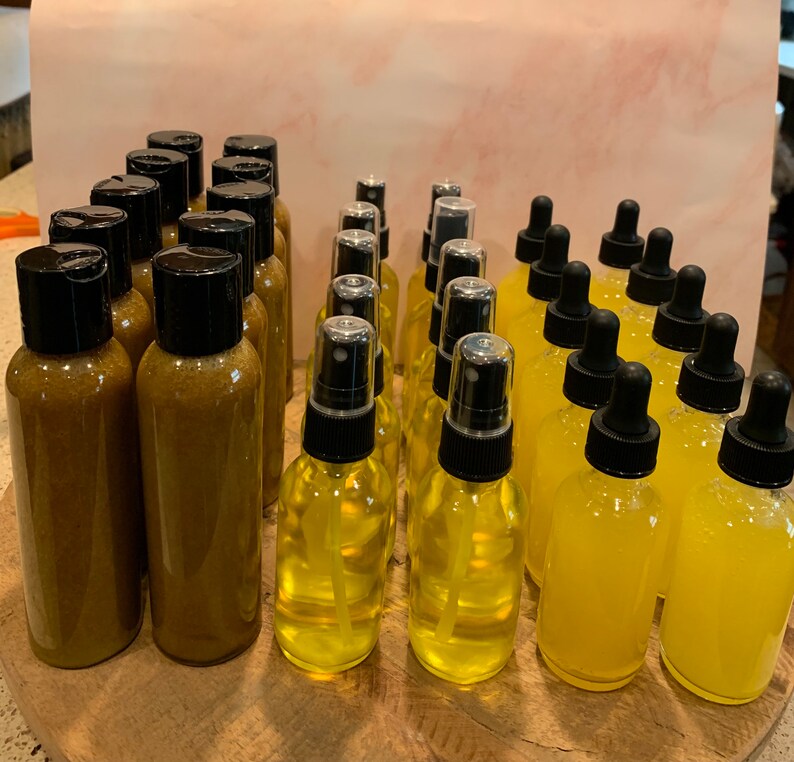 May include: A collection of amber and yellow glass bottles with black caps and spray tops. The bottles are arranged in rows on a wooden surface.