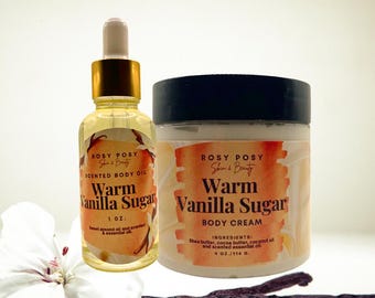 May include: A set of two body care products in a warm vanilla sugar scent. The set includes a 1 oz. scented body oil and a 4 oz. body cream. Both products feature a warm vanilla sugar scent and are packaged in clear glass bottles with black lids.