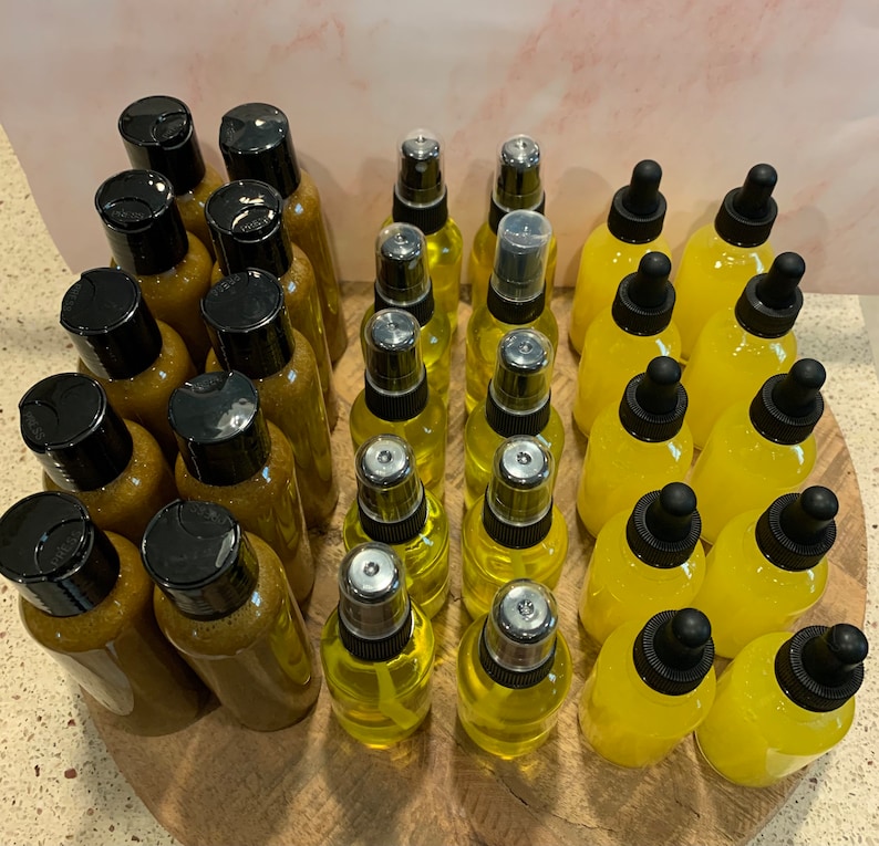 May include: A collection of amber and clear glass bottles with dropper and spray tops. The bottles are arranged in two rows on a wooden surface.