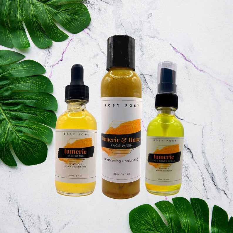 May include: Three glass bottles of turmeric face care products. The bottles are labeled "tumeric face serum", "tumeric & honey face wash", and "tumeric face toner spray".