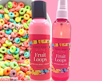 May include: Two pink bottles with white lids and labels. The labels say "Rosy Posy Skin & Beauty Fruit Loops Scented Body Cream" and "Rosy Posy Skin & Beauty Fruit Loops Scented Body Oil". The bottles are in front of a bowl of colourful cereal.