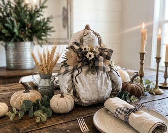 Rustic Farmhouse fabric pumpkin decoration adorned with a black-and-white buffalo plaid bow, burlap accents, twine, and faux flowers.