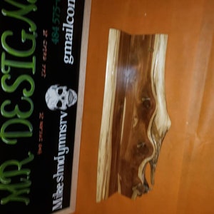 May include: A wooden sign with the text "MR. DESIGN" in green letters on a black background. The sign is framed in wood and has a skull graphic and contact information.