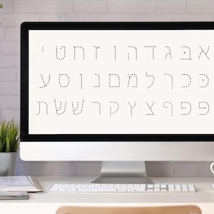 May include: A computer screen displaying a white background with a dotted outline of the Hebrew alphabet. The computer is on a white desk with a book, a potted plant, a cup, and a pencil holder.