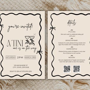 May include: A baby shower invitation with a whimsical design featuring two champagne glasses and the text "A'Tini one is on the way". The invitation includes details about the event, including the date, time, and location. It also includes information about the baby's registry and a diaper raffle.