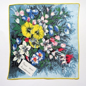 Könnte beinhalten: Ein blaues und weißes Seidentuch mit floralem Muster, gelbem Rand und dem Text "Pour vous Madame!" in Schwarz.
