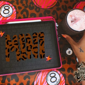 May include: A pink-framed tablet with the word "MAMI" in a leopard print design, with star accents. The background features a leopard print pattern and pink and orange billiard balls. A drink with a straw is held in a dark glass.