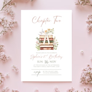 May include: A white invitation card with the text "Chapter Two" in a script font. It features a stack of books adorned with flowers and a ribbon. The invitation is for Sophia's 2nd birthday, with the date and time details.