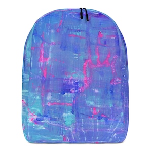 Puede incluir: Una mochila con un diseño abstracto. La bolsa presenta un patrón de pinceladas azules, turquesas y moradas con acentos rosas. La mochila tiene cordones negros en la parte superior.