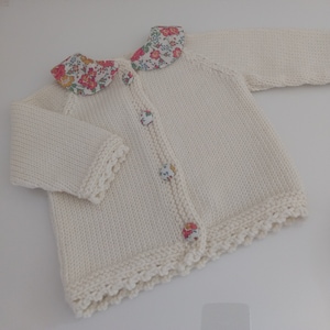 Peut inclure: Un cardigan blanc en tricot avec un col à imprimé floral et des boutons. Le cardigan a une bordure festonnée.