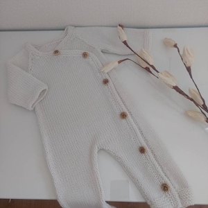 Pyjama bébé tricoté main en laine mérinos blanche associé à des boutons bois