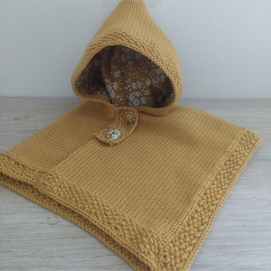Capa poncho com capuz para bebê tricotada à mão em lã merino mostarda forrada com tecido liberty