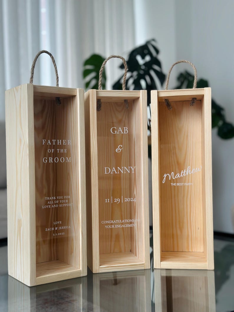 May include: Three wooden boxes with rope handles. The boxes are engraved with the text "Father of the Groom", "Gab & Danny 11|29|2024 Congratulations on your engagement", and "Matthew The Best Pappy".