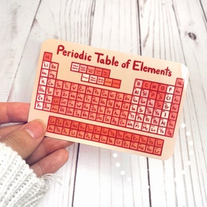 May include: A pink and orange periodic table of elements sticker with the title "Periodic Table of Elements".