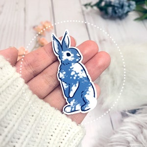 May include: A blue and white rabbit sticker with a white background. The rabbit is standing on its hind legs and has a white spot on its nose.