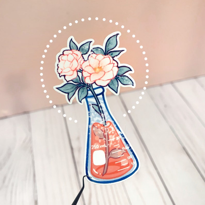 May include: A sticker of a white beaker with a pink flower stem inside. The beaker has markings for 250 ml, 150 ml, 100 ml, and 50 ml. The flower has two pink flowers and green leaves. The sticker is surrounded by a white dotted circle.