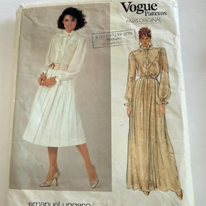 以下が含まれることがあります： エマニュエル・ウンガロによるVogue Patterns Paris Originalの型紙封筒、番号2908。表面には、フリル付きの襟とプリーツスカートを備えた長袖ドレスのイラストが2種類描かれており、膝丈とフルレングスの両方のバージョンが示されています。