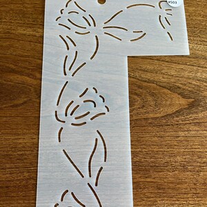 May include: White plastic stencil with a floral design. The stencil has a number #503 printed on it.