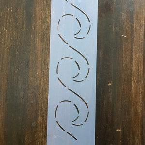 May include: A white plastic quilting stencil with a repeating pattern of curved lines and circles. The stencil is designed for use with a sewing machine.