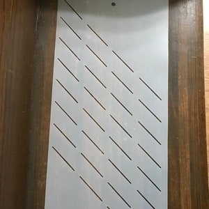 May include: White plastic stencil with a diagonal pattern of thin lines. The stencil is designed for crafting and decorating projects.