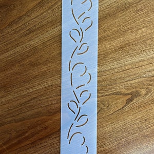 May include: A blue plastic stencil with a floral design. The stencil is labeled #23.