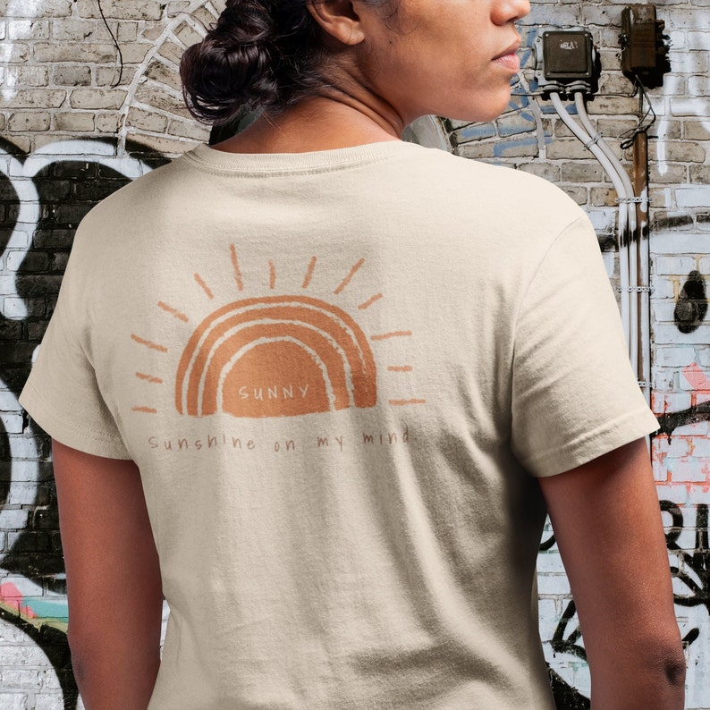 Puede incluir: Una camiseta beige con un gr&aacute;fico de un sol con el texto "Sunny Sunshine on my mind" impreso en la espalda.